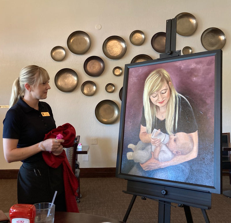 Client Jessie receiving her custom commissioned portrait painting of her and her baby by Candi Kloverstrom